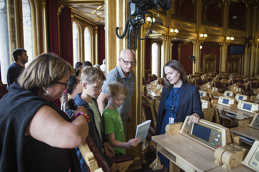 Thea fra seksjon for besøk og formidling viser frem stortingssalen under en av sommeromvisningene i 2016. Stortingets omvisere forteller blant annet om husets historie og arkitektur, det politiske systemet og kunsten på veggene. Foto: Stortinget.