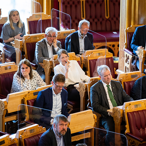 Representanter i stortingssalen sitter med plekisglass mellom plassene av smittevernhensyn under stortingsmøtet tirsdag 26. mai. Foto: Stortinget