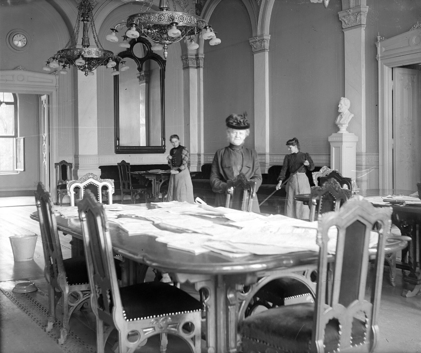 Stortingets oldfrue og renholdsassistenter i forsamlingssalen (nåværende Eidsvollsgalleriet), ca. 1900.
