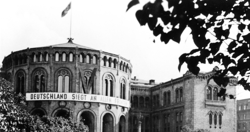 Stortingsbygningen under andre verdenskrig, med tysk propagandaplakat og hakekors i flaggstangen.